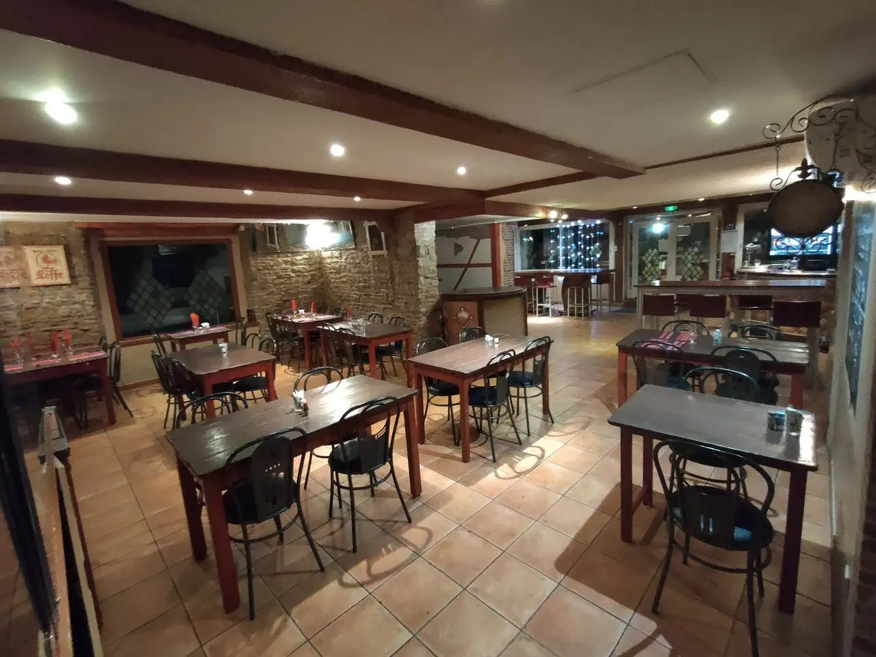 Salle intérieure du restaurant Mont Relais Gaillard, avec tables en bois, murs en pierre et poutres apparentes.