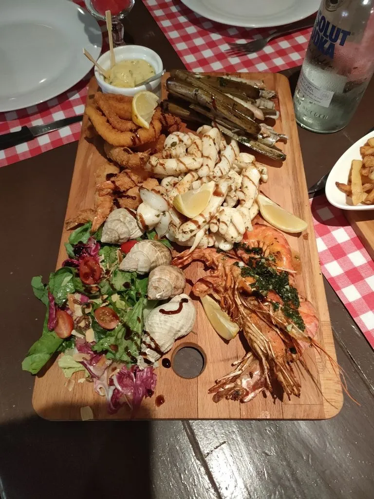 Pareillade de la mer avec crevettes, calamars, coquillages et salade sur une planche en bois.