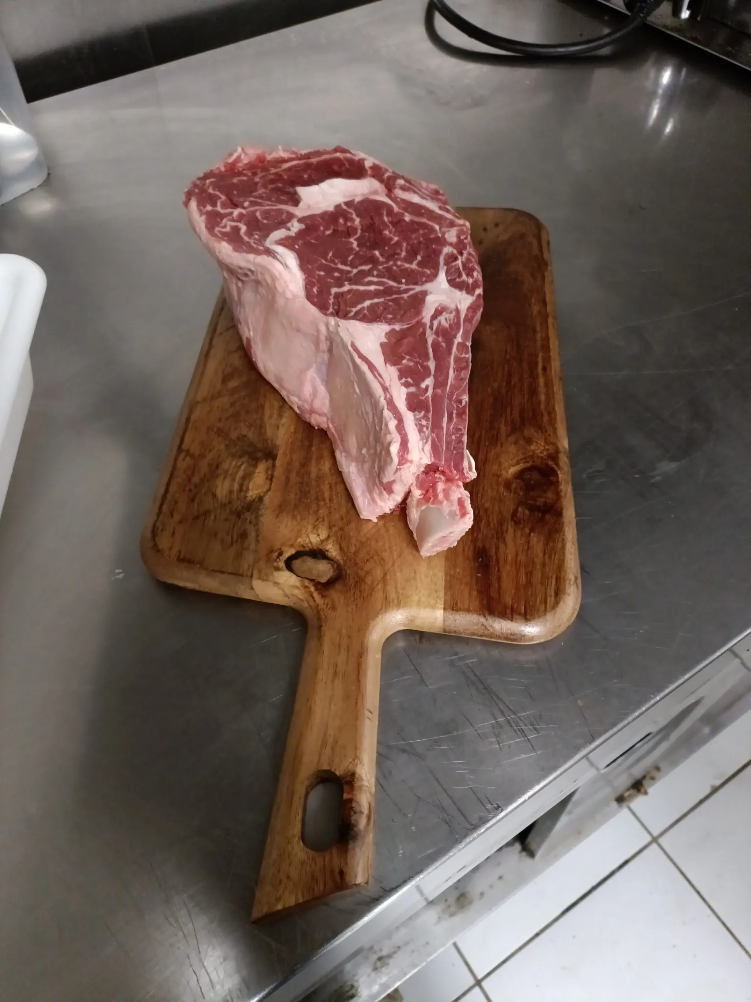 Épaisse pièce de bœuf crue sur une planche en bois dans la cuisine du restaurant Mont Relais Gaillard.