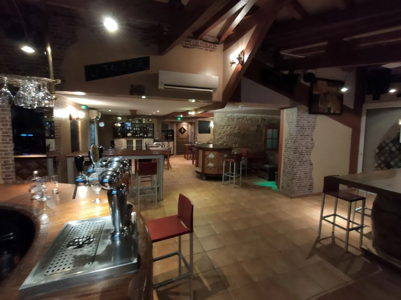 Intérieur du bar pub Mont Relais Gaillard, avec tireuses à bière, tables en bois et poutres apparentes.