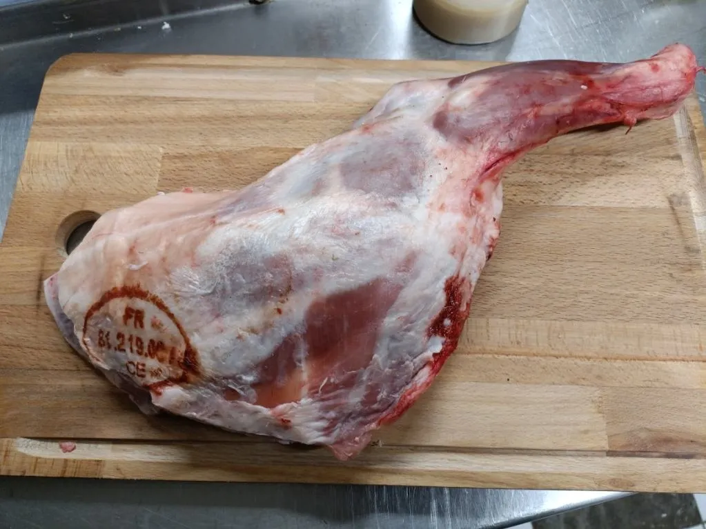 Pièce de viande crue posée sur une planche en bois dans une cuisine professionnelle.